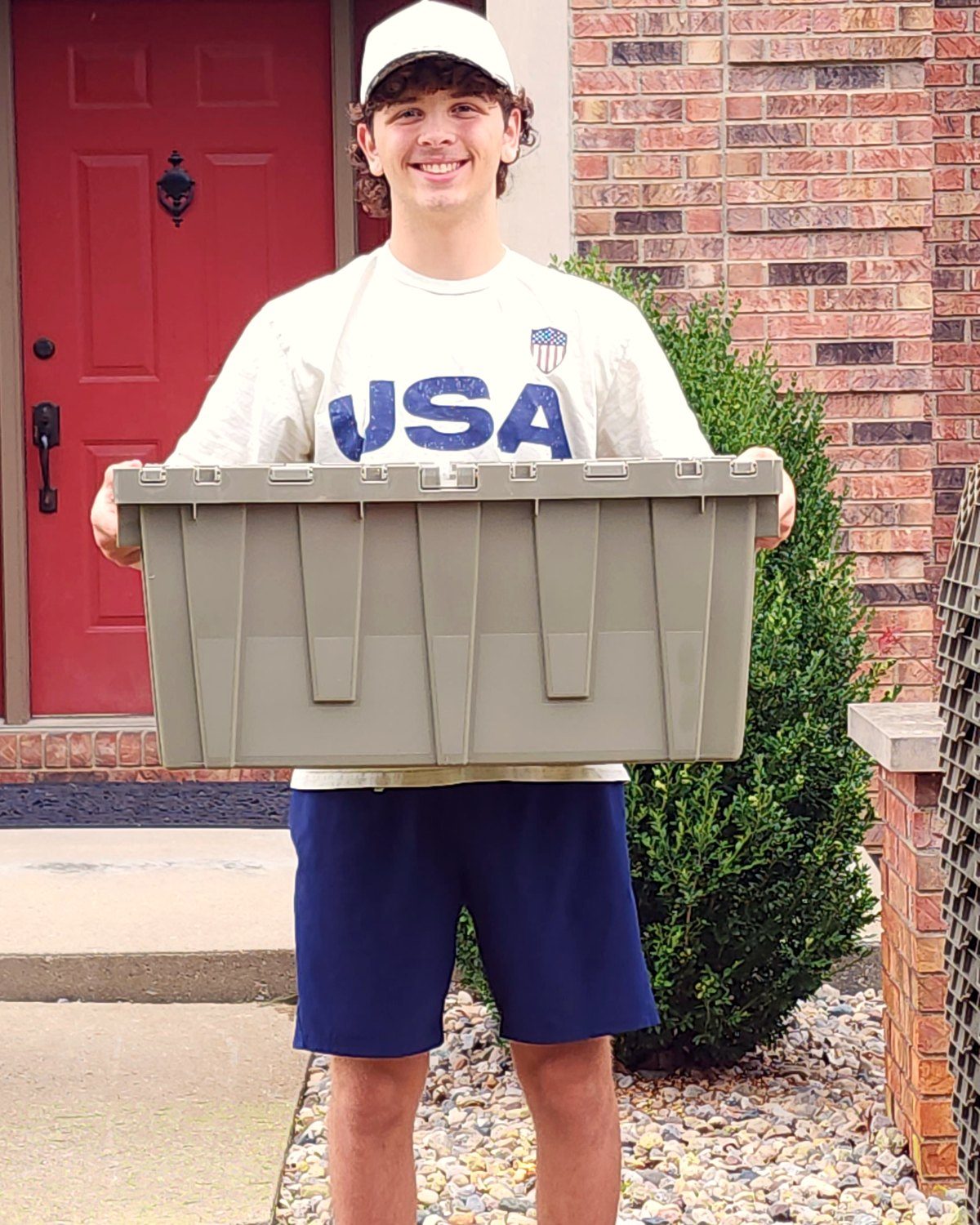 A person holding one CrateMoreSpace moving tote in front of them, showing its size